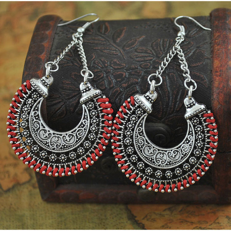 Pair of silver and red earrings on a textured surface
